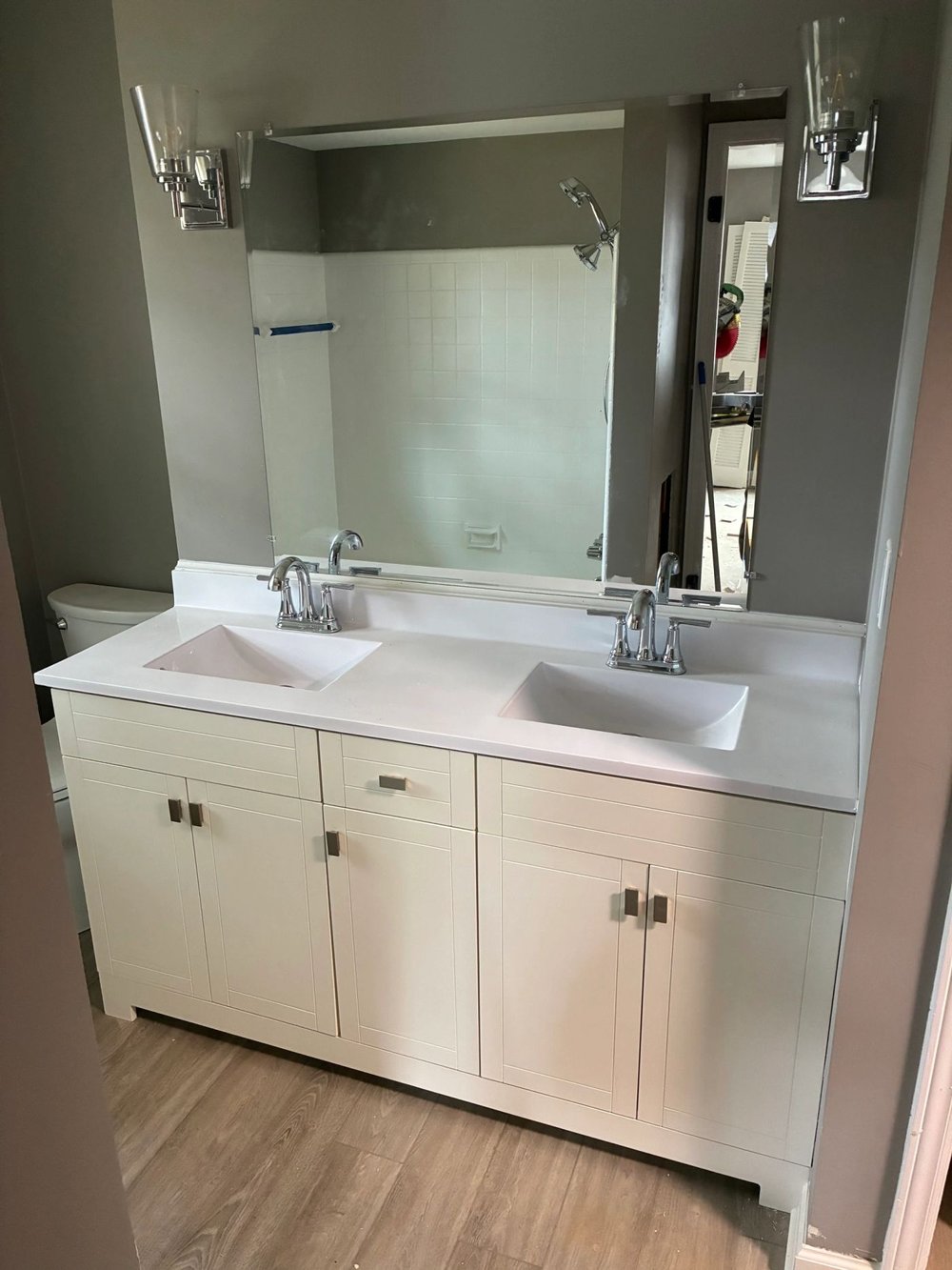 Bathroom with a new double vanity, cabinets, countertop and wall lighting